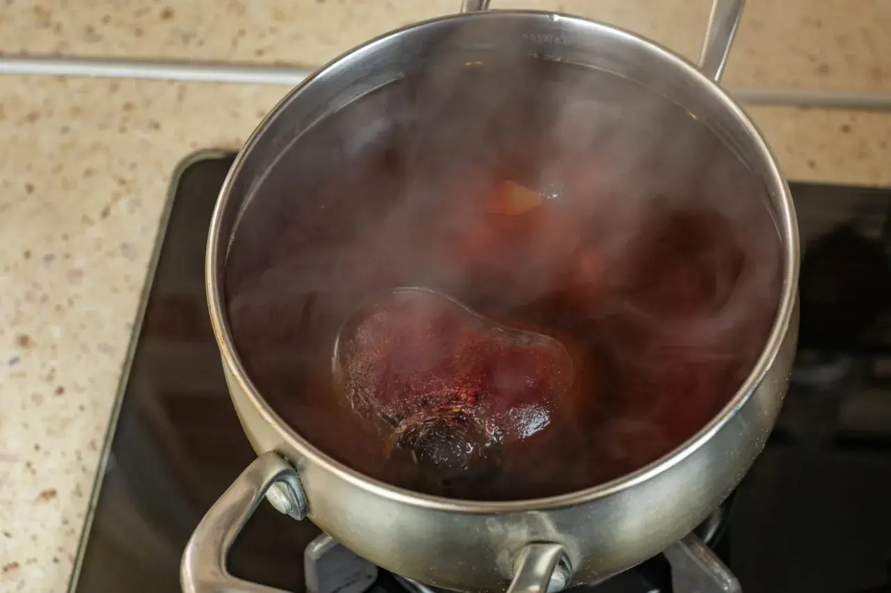 Cuisson de betteraves rouges dans une casserole d'eau bouillante. La vapeur s'échappe de la cocotte.