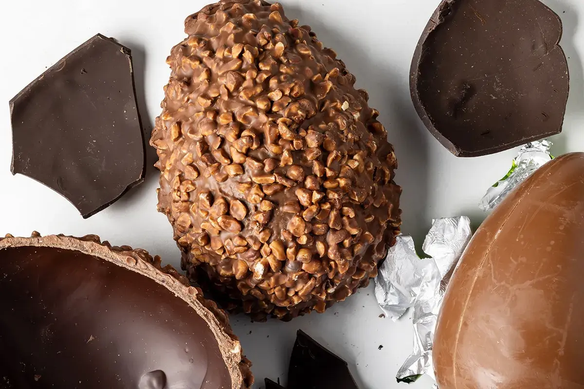 Uova di Pasqua al cioccolato, una con nocciole, altre rotte. Un assaggio delle loro origine.