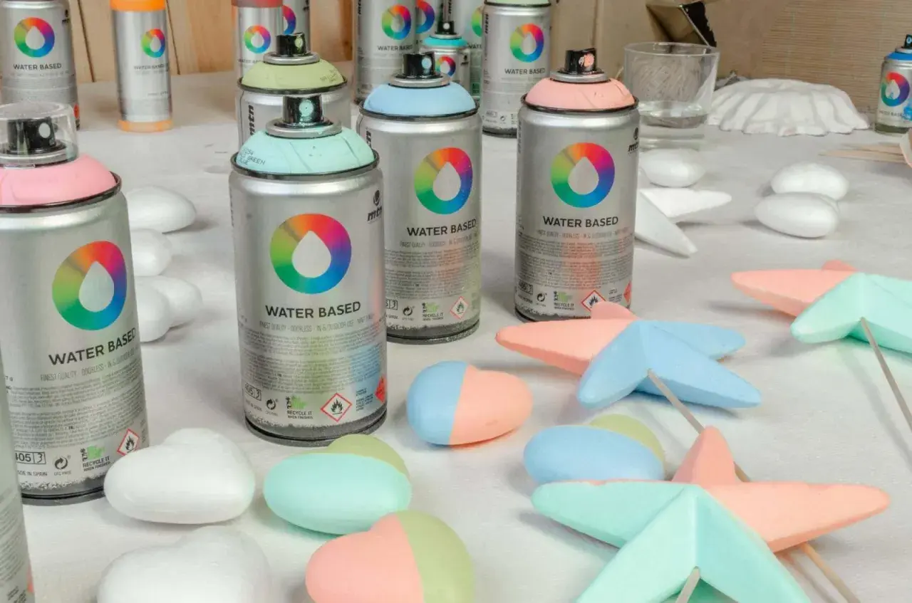Latas de spray de pintar espuma poliuretano en tonos pastel, listas para dar color a figuras de poliestireno.