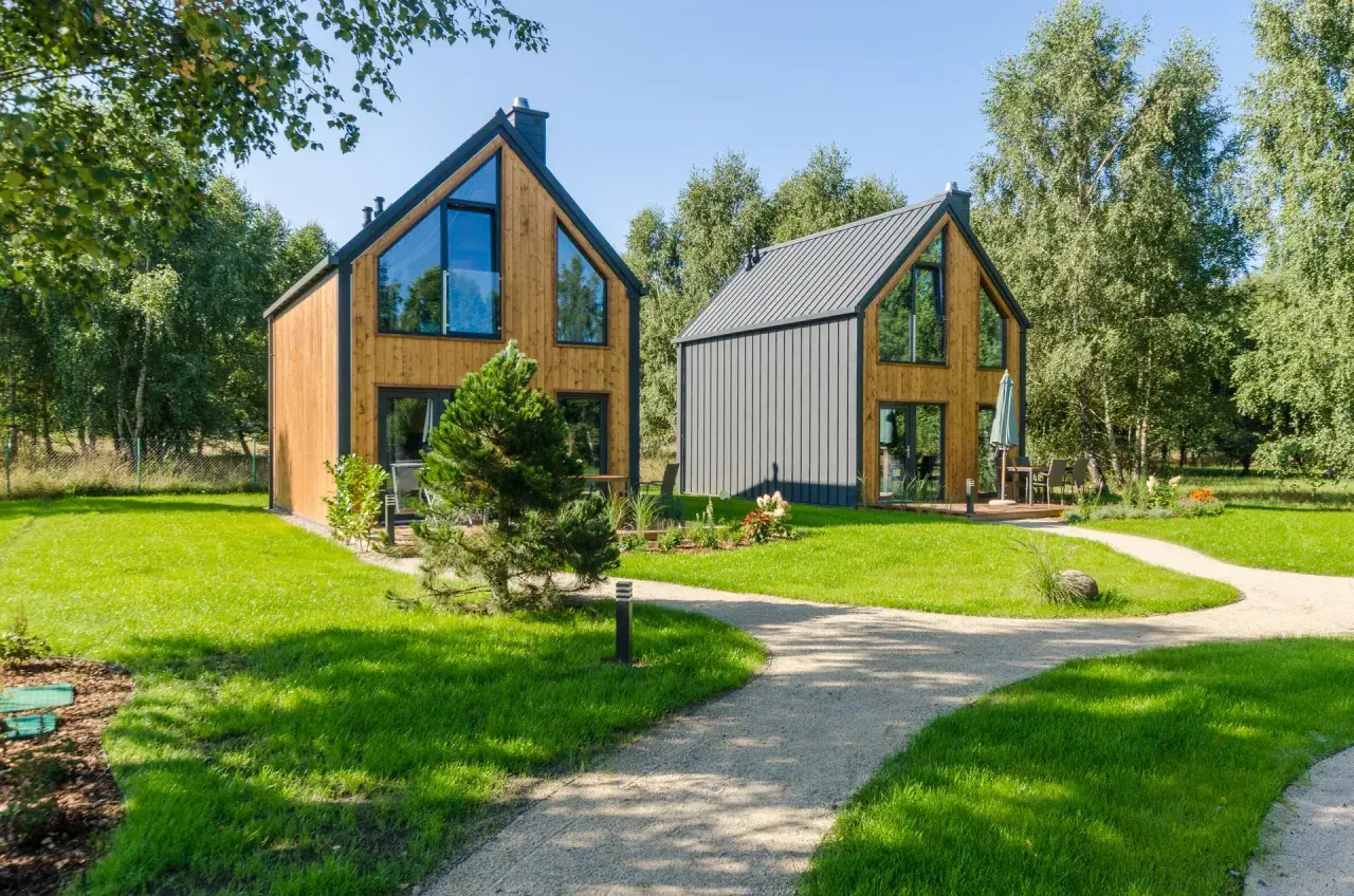 Nowe, nowoczesne domki w lesie nad morzem, otoczone zielenią i ścieżkami.