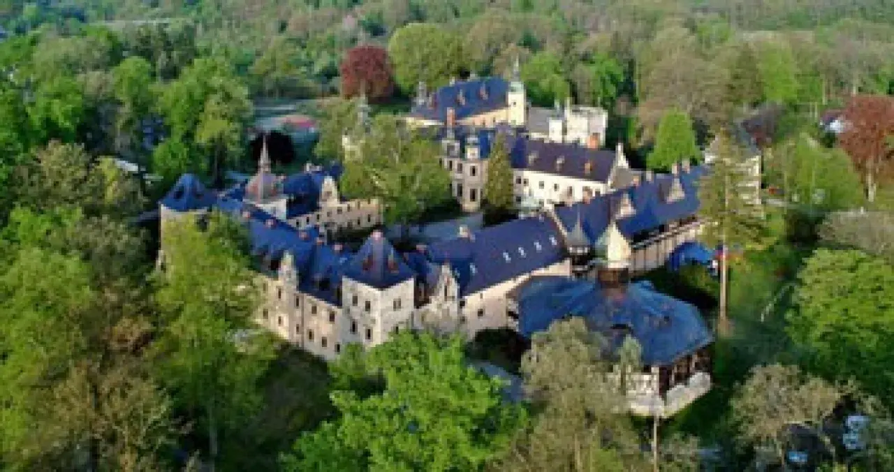 Zamek Kliczków z lotu ptaka, otoczony zielenią. Widać liczne skrzydła i wieżyczki, sugerujące bogactwo pokoi i historii.