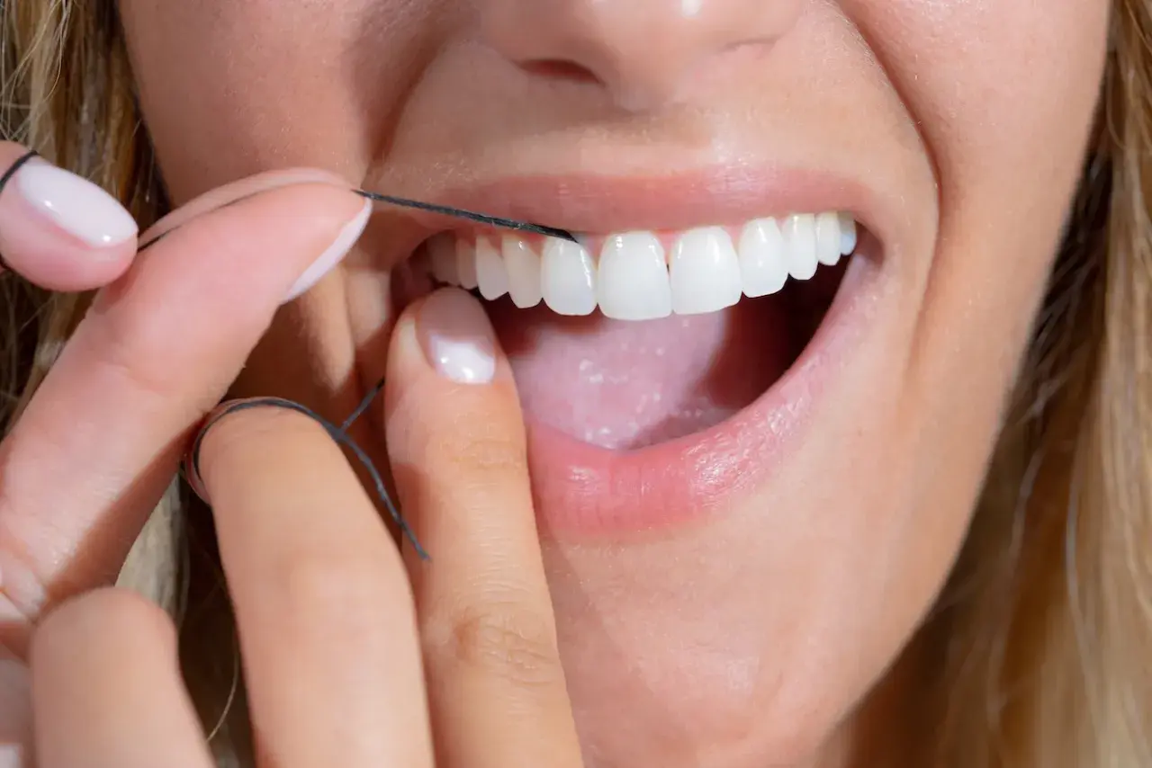 Dita curate usano filo interdentale abrasivo per pulire i denti bianchi e brillanti.