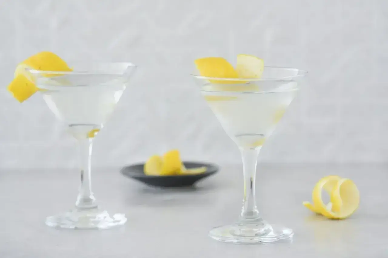 Dwa eleganckie drinki z martini, ozdobione skórką cytrynową, czekają na spróbowanie.
