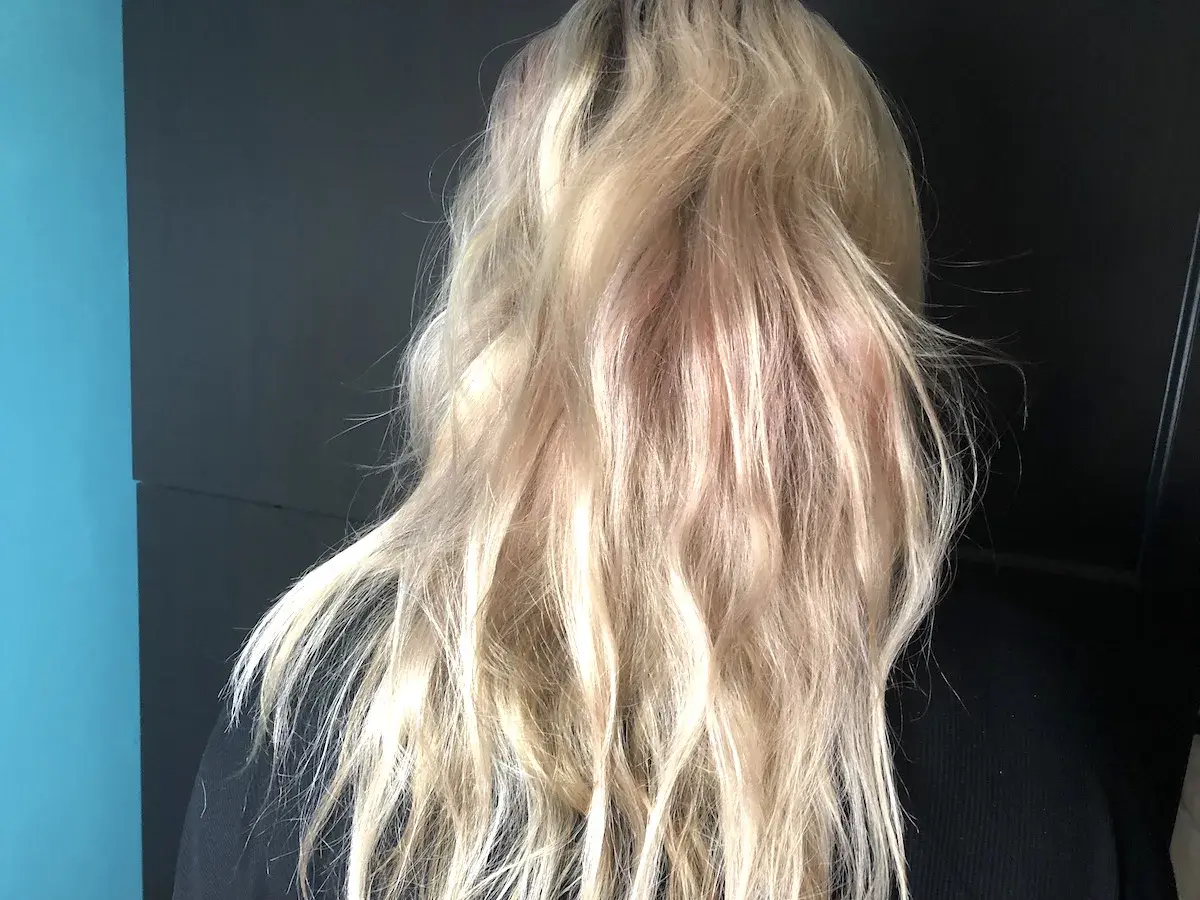 En person med blont, vågigt hår med inslag av rosa nyanser. En ny hårfärg som ger en unik look.