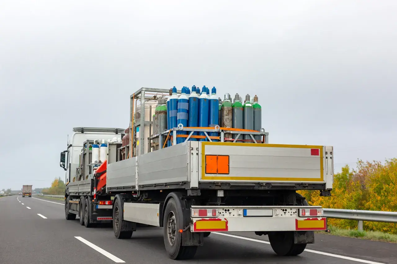 Ciężarówka z butlami gazowymi, klasa 2 ADR, jedzie autostradą.