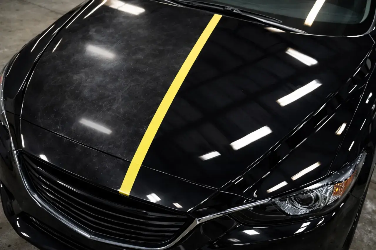 Czarne auto z żółtym pasem dzielącym maskę na część zmatowioną i błyszczącą.