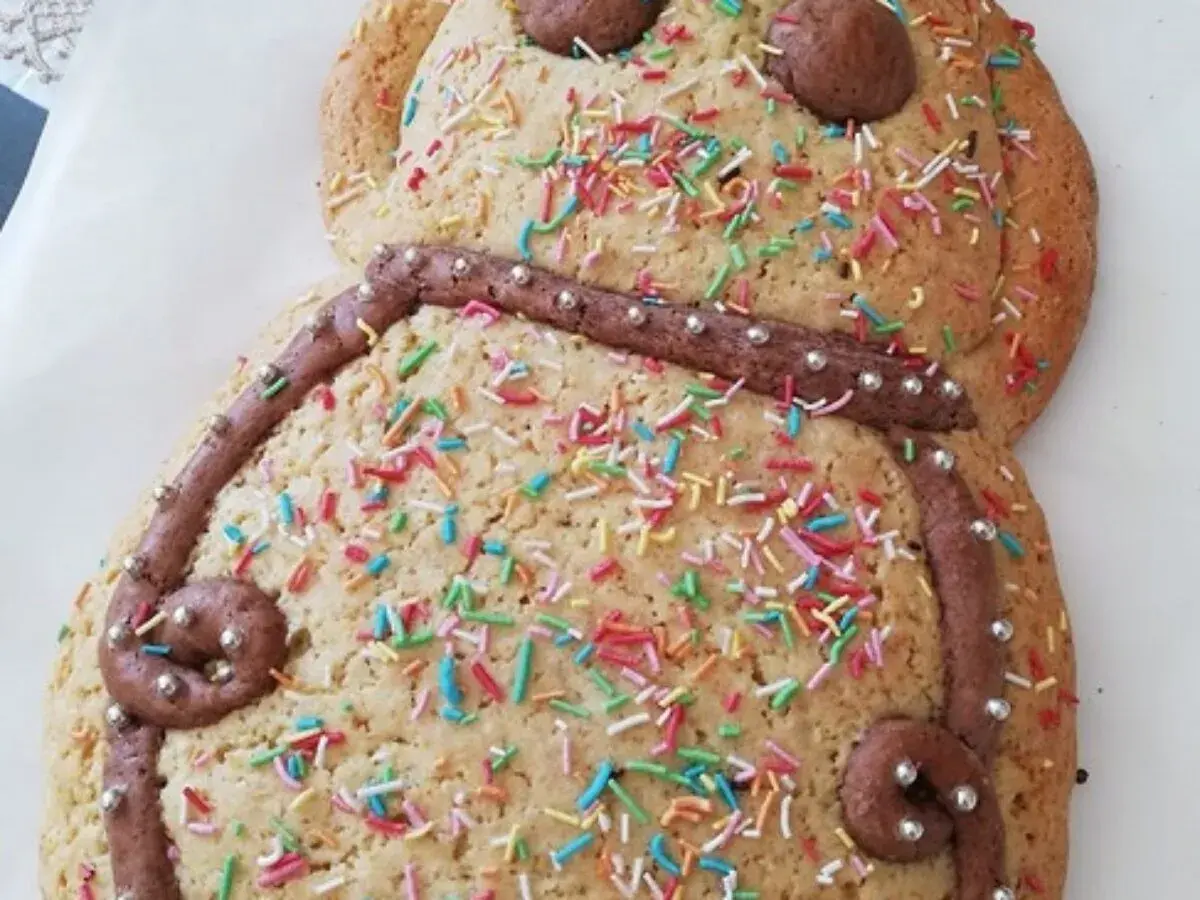 Dolce a forma di pupazzo, decorato con glassa al cioccolato, zuccherini colorati e perline argentate. Una deliziosa ricetta pupa abruzzese pronta da gustare.