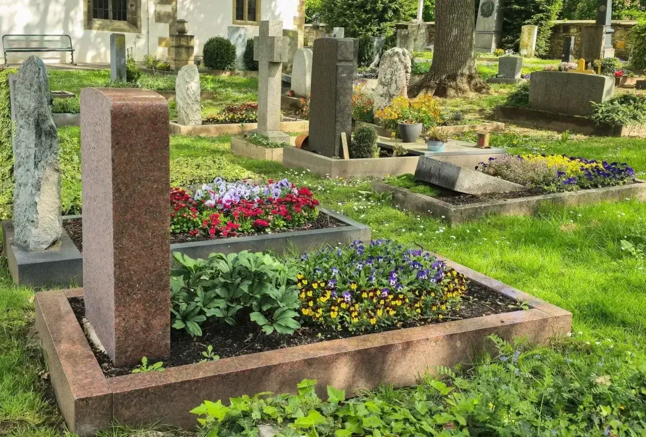 Cmentarz z zadbanymi nagrobkami i kwitnącymi kwiatami. Każdy grób to symbol prawa do grobu i pamięci.