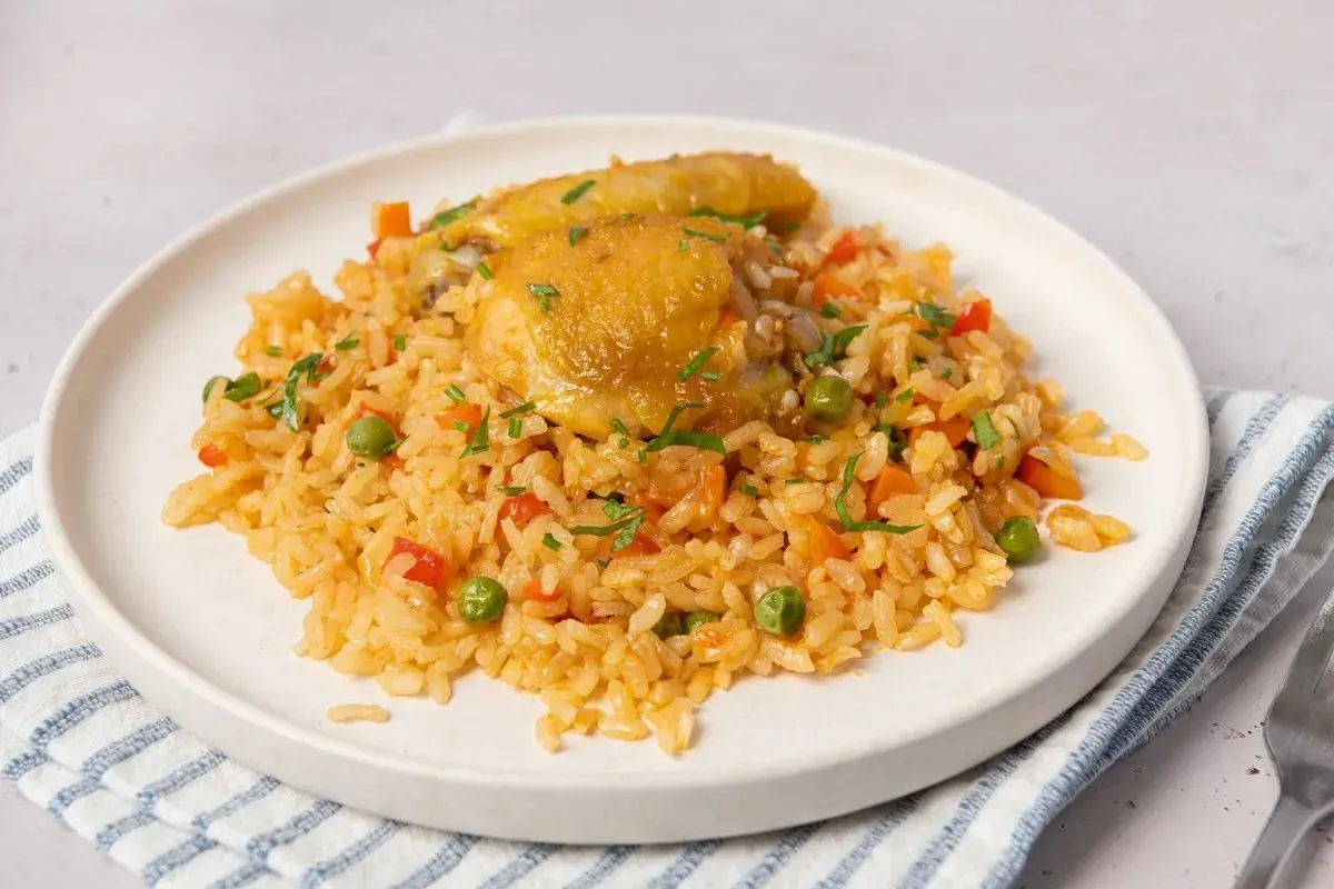 Plato de arroz con pollo, zanahorias, guisantes y pimientos rojos. Una deliciosa receta de arroz con pollo lista para servir.
