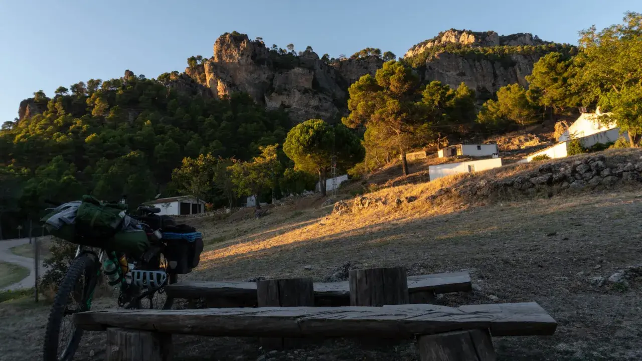 Bicicleta cargada para aventura, lista para explorar el GR 247 en bici. Paisaje montañoso al atardecer.