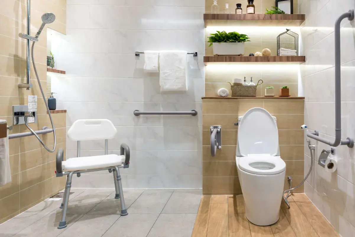 Baño moderno con duchas adaptadas para personas mayores, asiento de ducha, barras de apoyo y un inodoro.