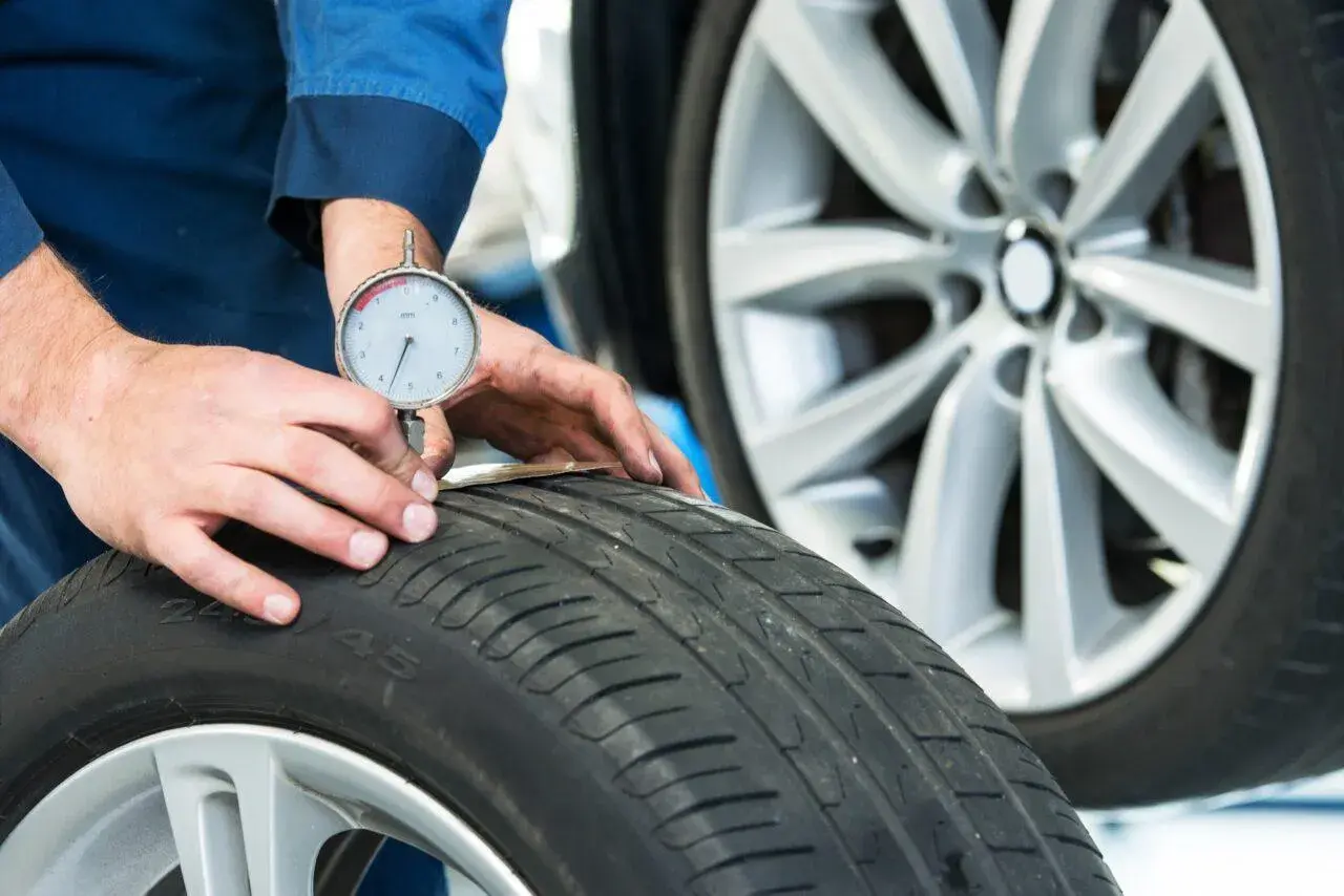 Un meccanico misura il battistrada di uno pneumatico 4 stagioni per capire quanti km fanno ancora.
