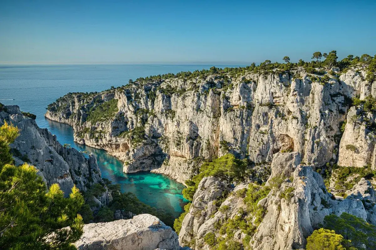 Vue spectaculaire depuis le belvédère d'En Vau sur la calanque aux eaux turquoise, entourée de falaises calcaires et de pins.