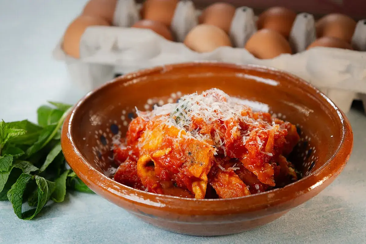 Frittata in trippa, un piatto saporito con uova e trippa in salsa di pomodoro, guarnito con parmigiano.