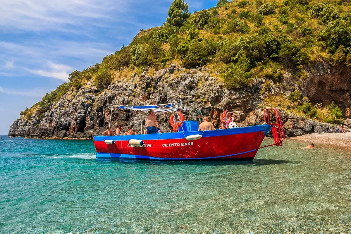 Gita in barca a Marina di Camerota, con gente che si gode il mare cristallino e la costa rocciosa. Perfetto per scoprire cosa fare a Marina di Camerota.