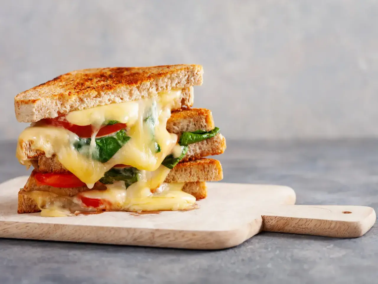 Un délicieux sandwich grillé aux tomates et épinards, une idée sandwich froid simple et gourmande. Le fromage fondant coule sur les tranches de pain.