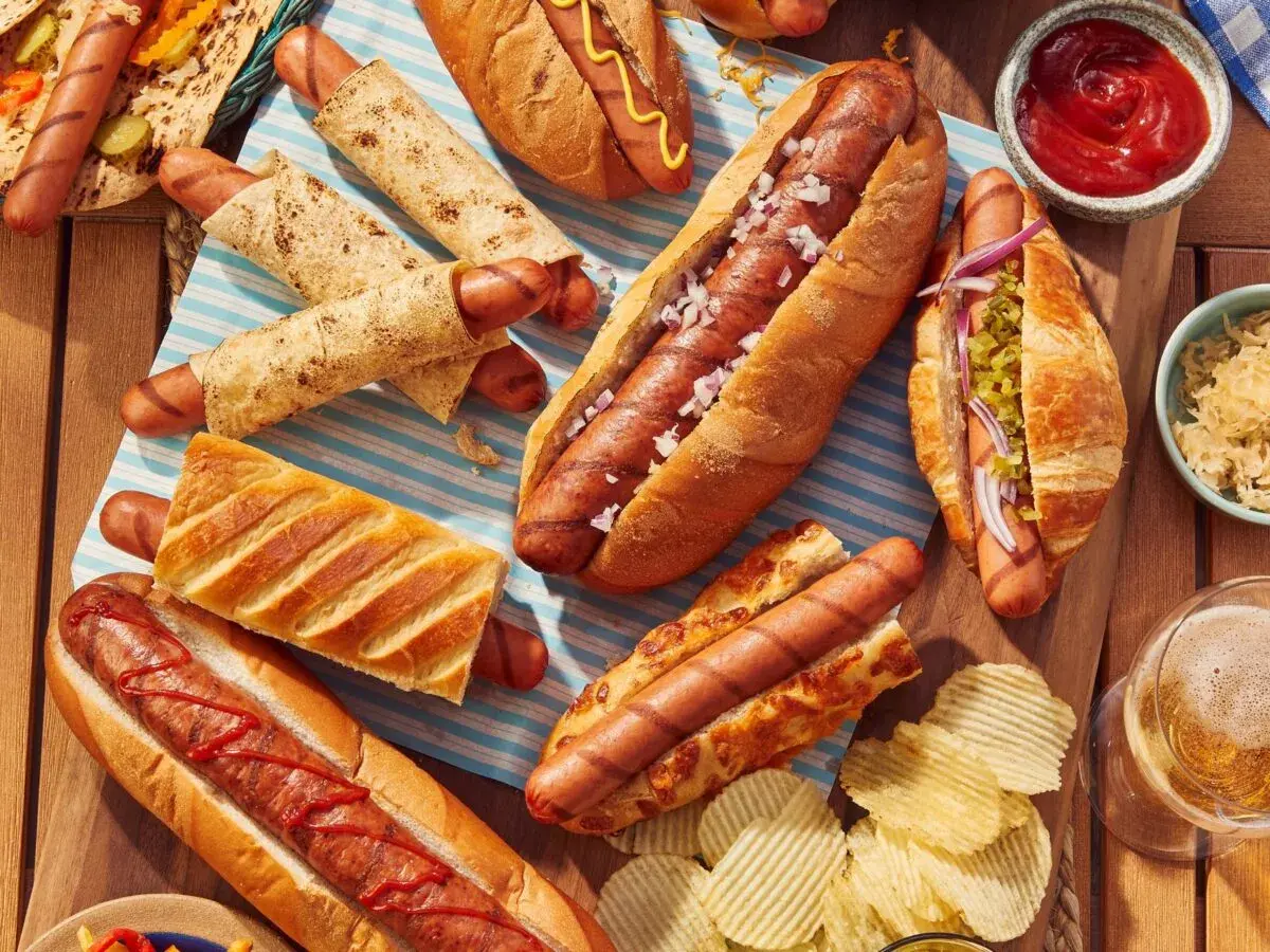 Un festin de hot-dogs pour un barbecue : pains variés, garnitures et chips.