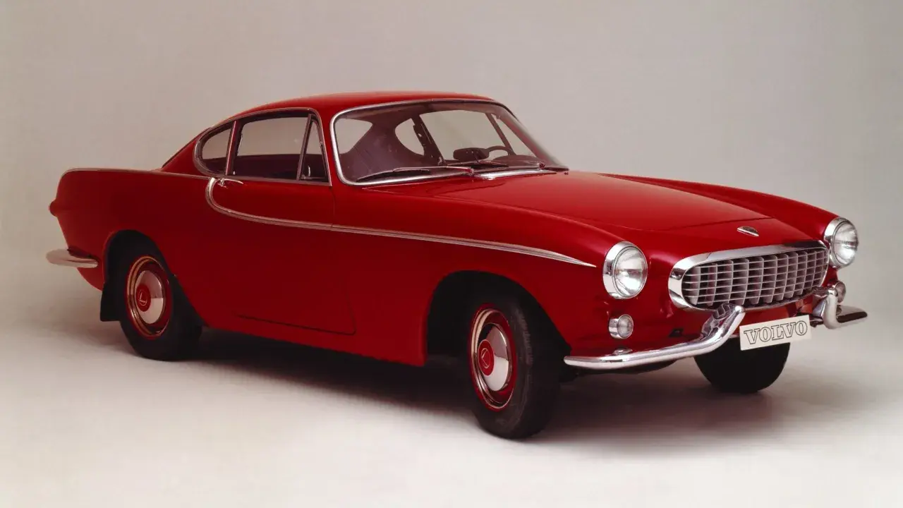 Une élégante Volvo rouge, un modèle emblématique des années 50, se dresse fièrement sur un fond neutre.
