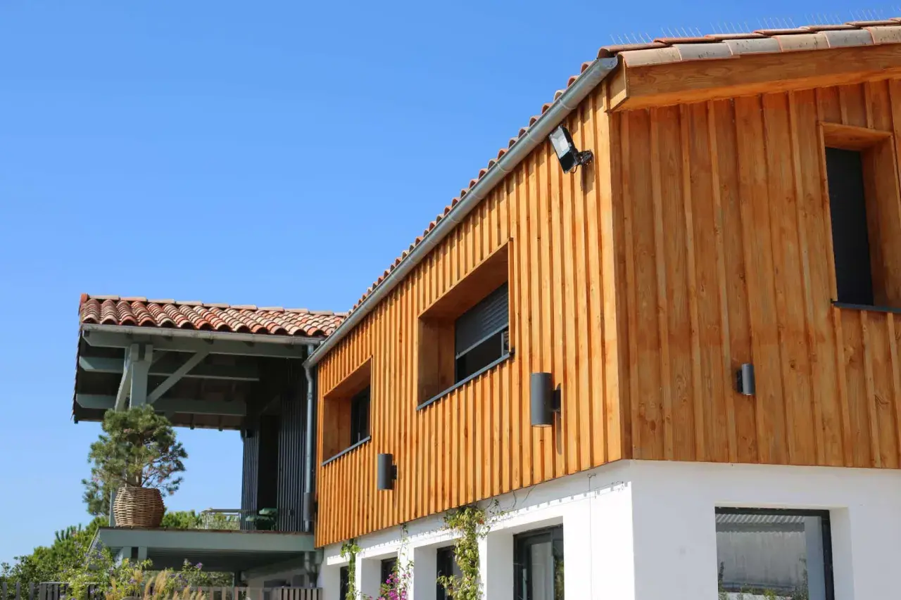 Bardage en bois naturel, un choix idéal pour l'extérieur. La maison moderne arbore des lames de bois clair sous un ciel bleu.