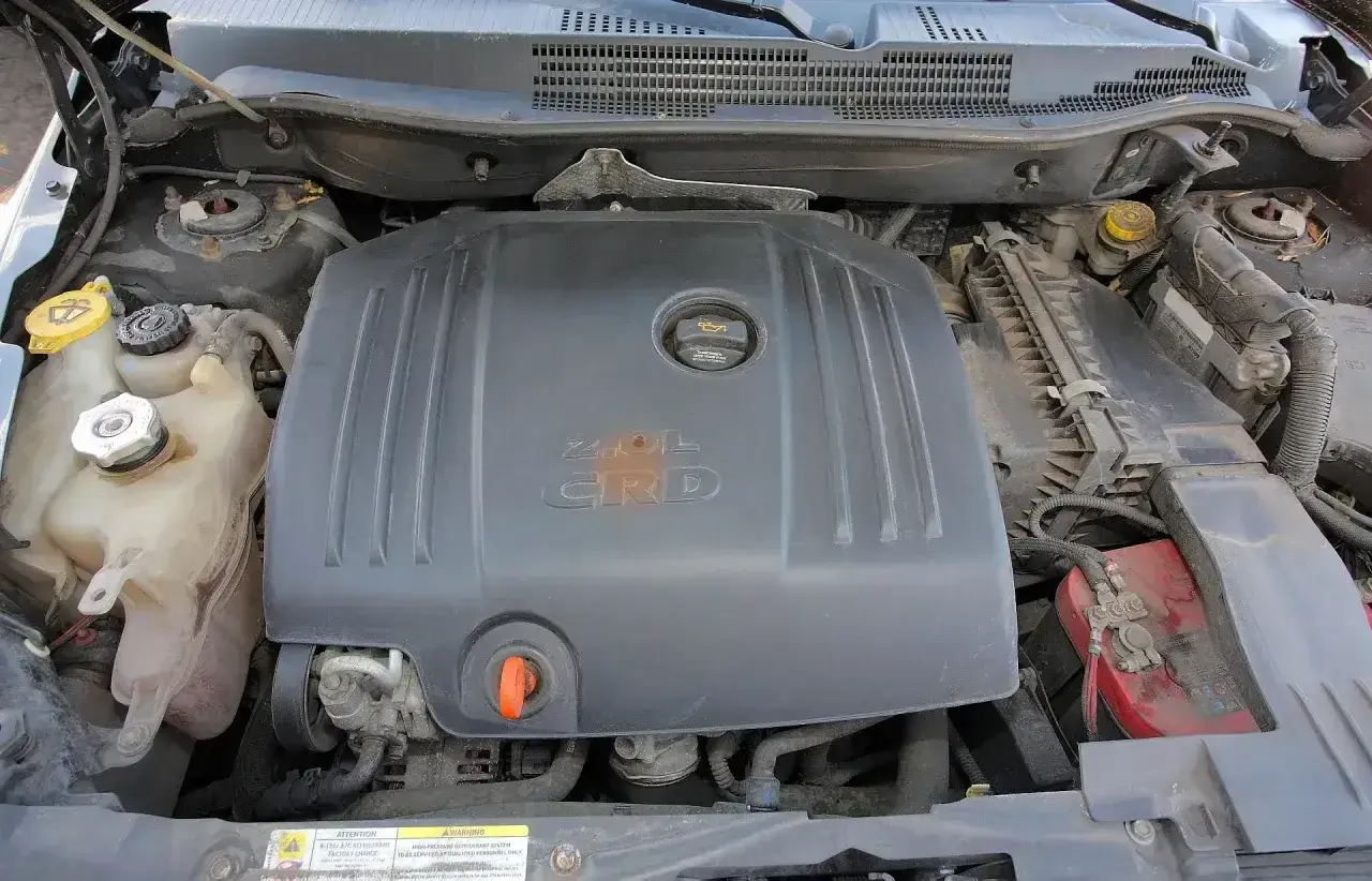 Silnik 2.0L CRD w Dodge Caliber. Widoczne zbiorniczki płynów i akumulator.
