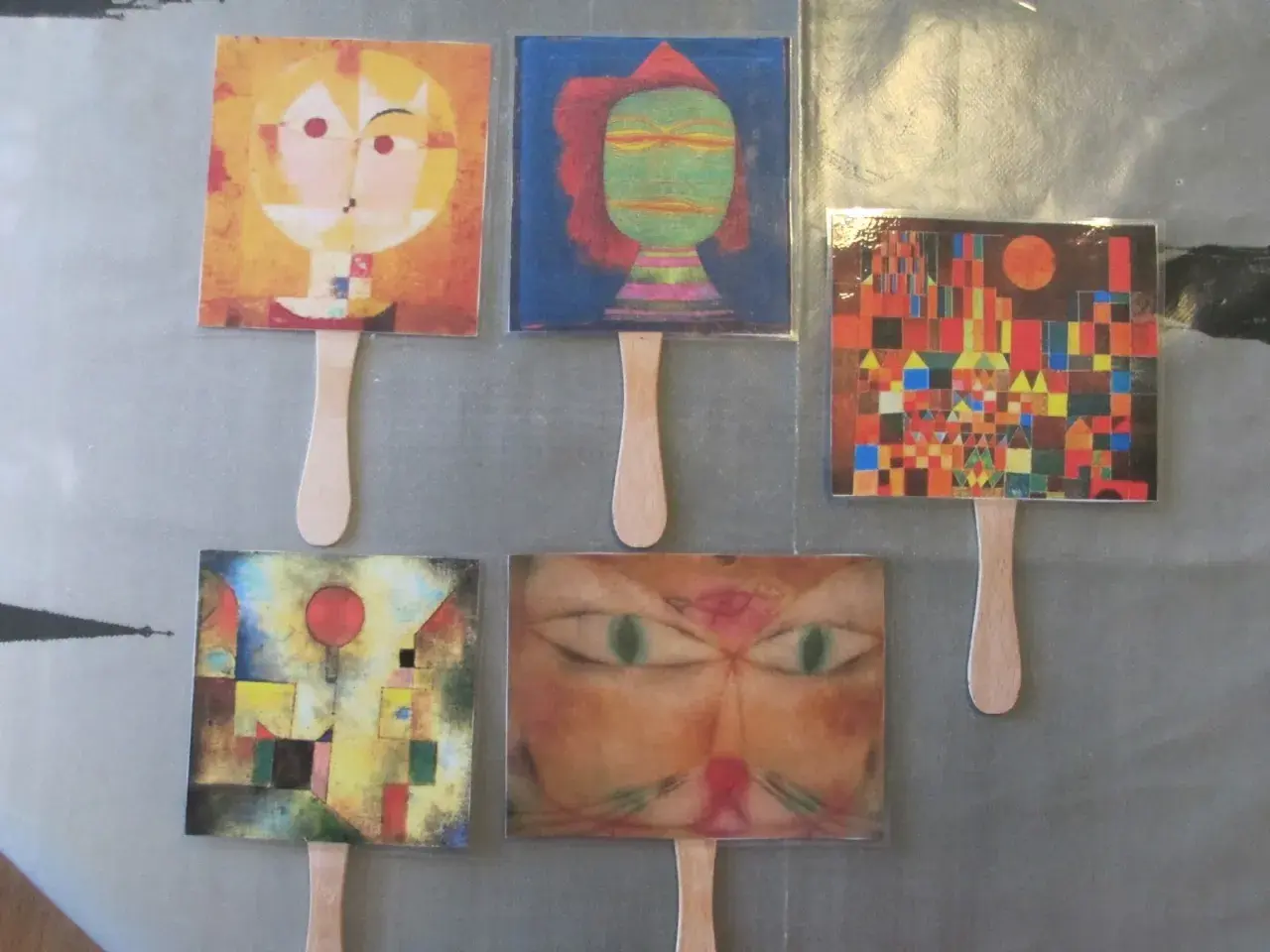 Marionetas con obras de Paul Klee para niños: rostros abstractos, un gato y un paisaje urbano colorido.