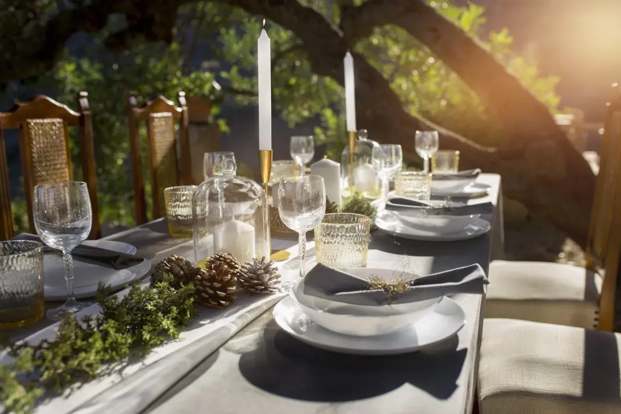 Tavola apparecchiata all'aperto con candele, pigne e rami, evocando un'atmosfera rustica e raffinata, perfetta per una cena nelle cantine di Firenze.