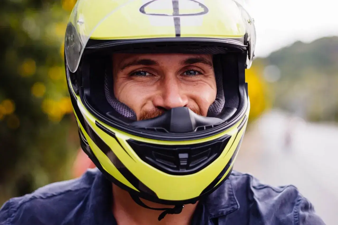 Uśmiechnięty mężczyzna w żółtym kasku motocyklowym.