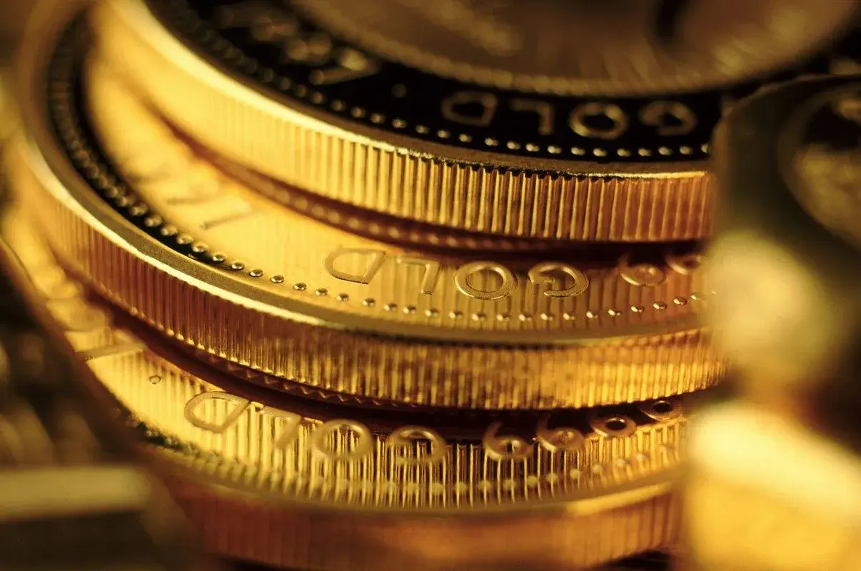 Zbliżenie na stos złotych monet z widocznym napisem "GOLD".