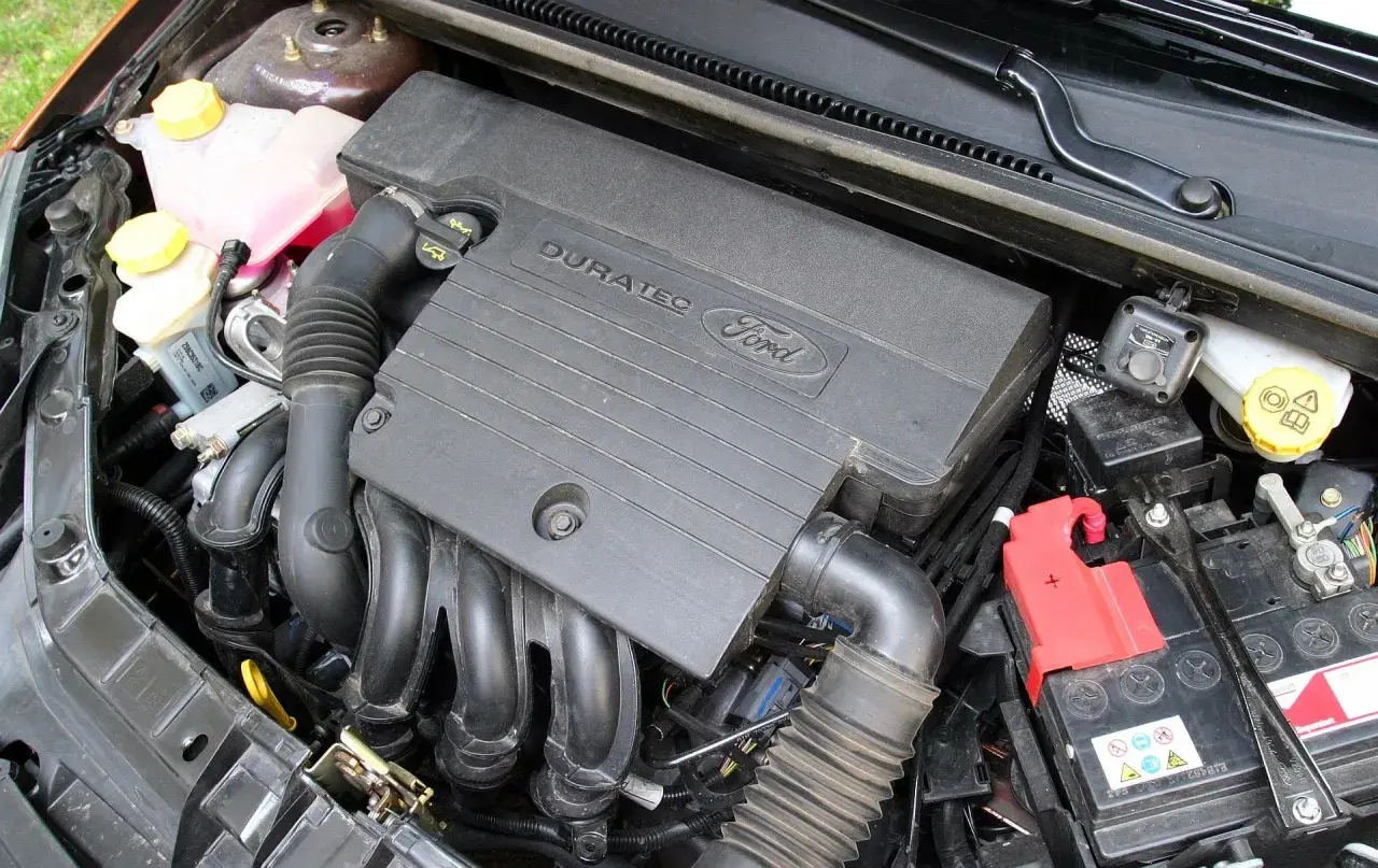Silnik Duratec w Fordzie Fiesta Mk6. Widoczny jest czarny plastikowy kolektor, przewody i akumulator.