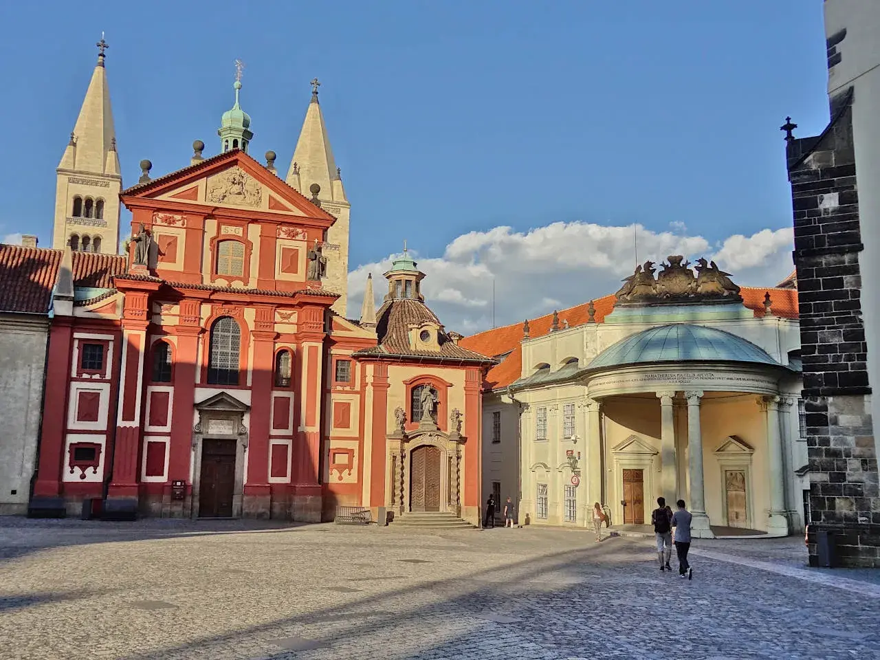 Visite à Prague : la place pavée devant la basilique Saint-Georges et le monastère, avec des touristes se promenant sous un ciel bleu.