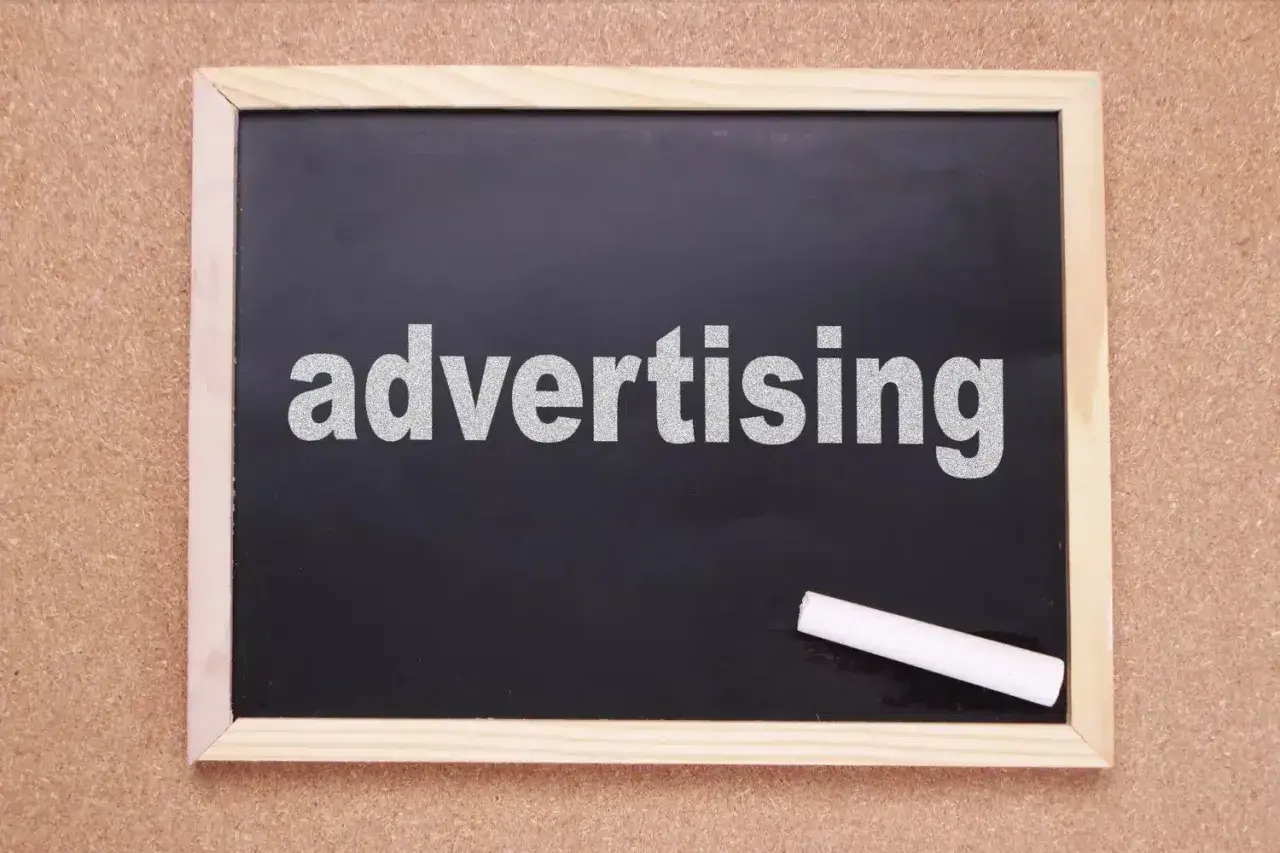 Tablica z napisem "advertising" i kredą. Czas na rymowane hasła reklamowe, które przyciągną uwagę!