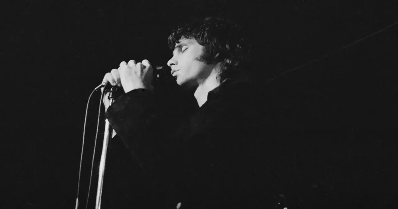 Jim Morrison z The Doors śpiewa do mikrofonu, zamykając oczy.