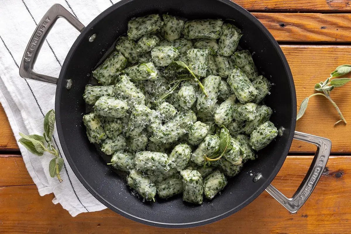 Strangolapreti alla trentina fumanti in padella, conditi con burro fuso, salvia e parmigiano.