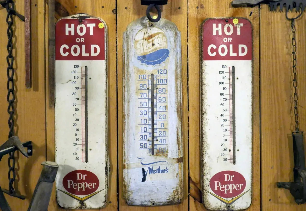 Trzy stare termometry wiszą na drewnianej ścianie. Dwa z nich reklamują Dr Pepper, jeden pokazuje "Ay Weather's". Idealne do monitorowania temperatury w biurze.