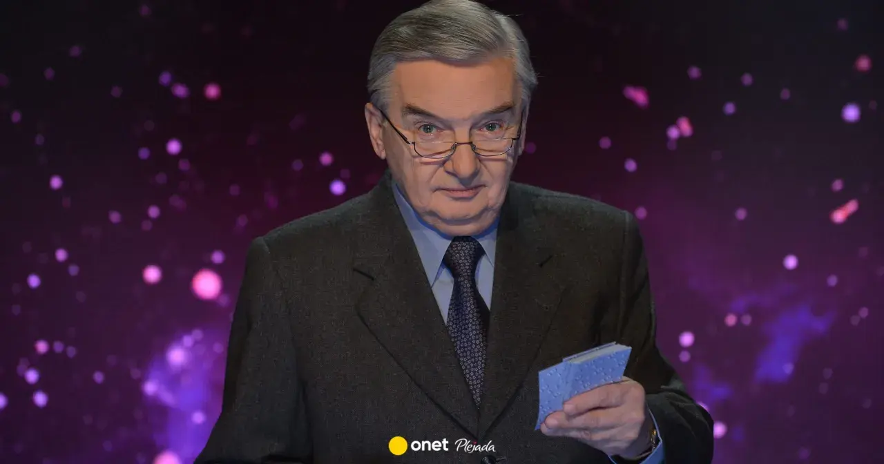 Tadeusz Sznuk w garniturze, z okularami na nosie, trzyma w dłoni małe niebieskie karty. Może to być nawiązanie do jego żony, która kiedyś grała w karty.