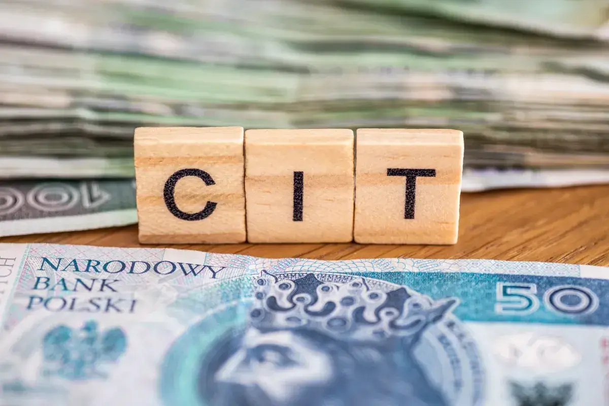 Drewniane klocki z literami "CIT" na tle polskich banknotów. Kluczowe dla dokumentacji cen transferowych.