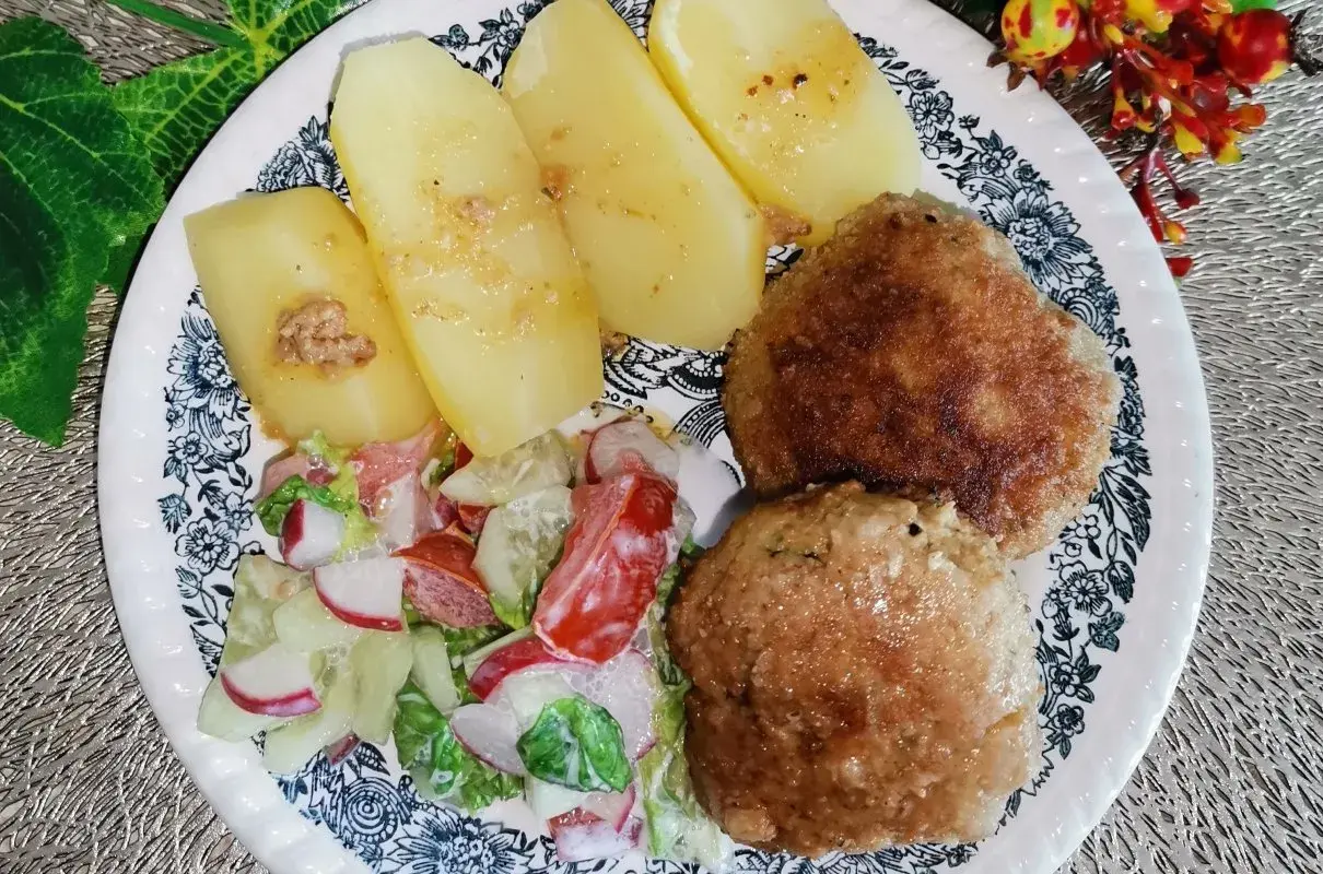 Dwa kotlety mielone z majonezem, ziemniaki i surówka z rzodkiewki i pomidora.