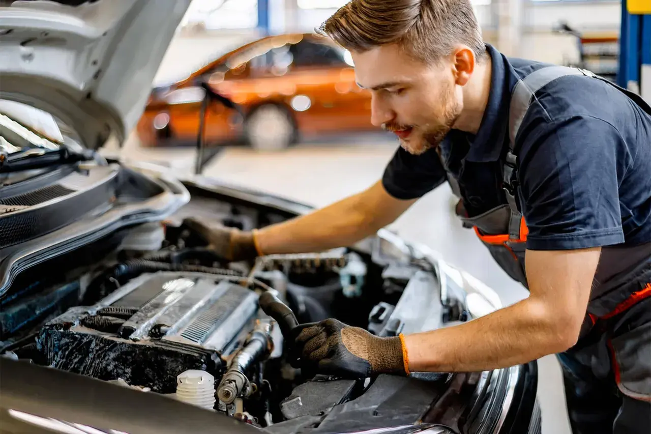 Mécanicien travaillant sur le moteur d'une voiture. Il explique comment changer une batterie de voiture sans perdre les données.