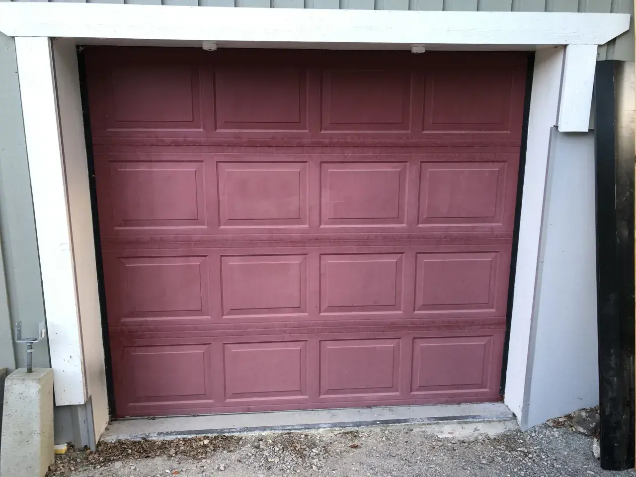 En mörkröd garageport i aluminium, redo att måla om för ett fräschare utseende.