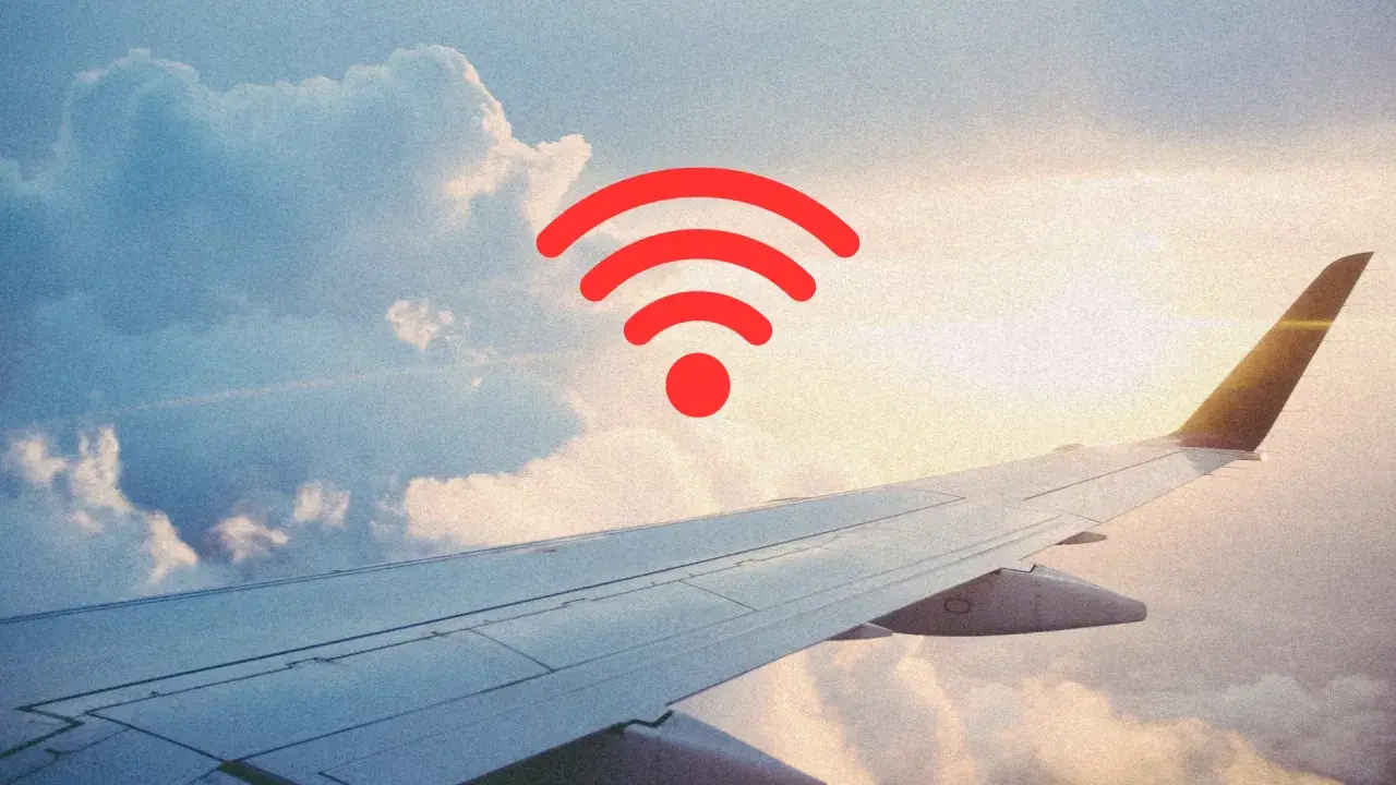 Widok z okna samolotu na chmury i skrzydło. Czerwony symbol Wi-Fi sugeruje, czy w samolocie jest wifi.