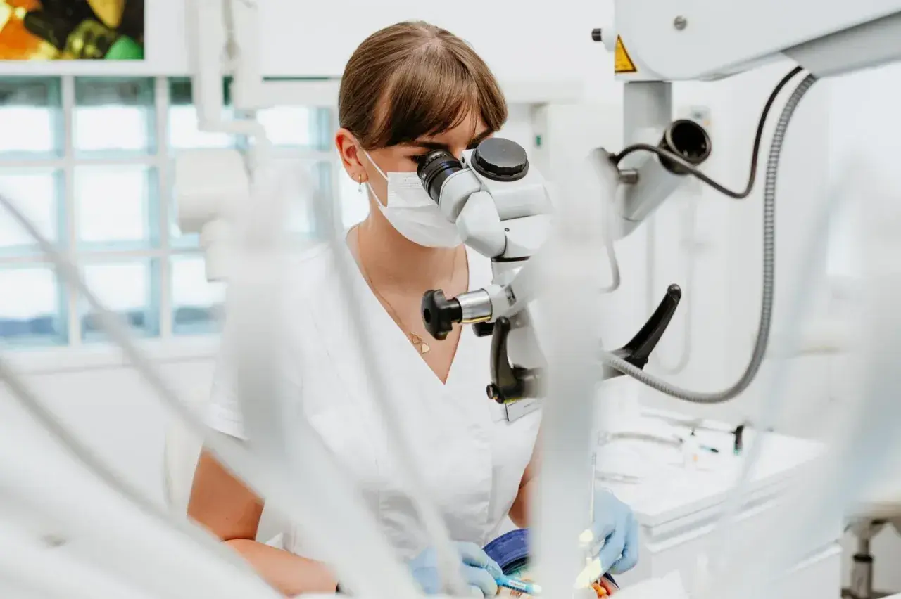 Dentystka pod mikroskopem. Zastanawiasz się, ile kosztuje wypełnienie zęba? Precyzyjna praca stomatologa.