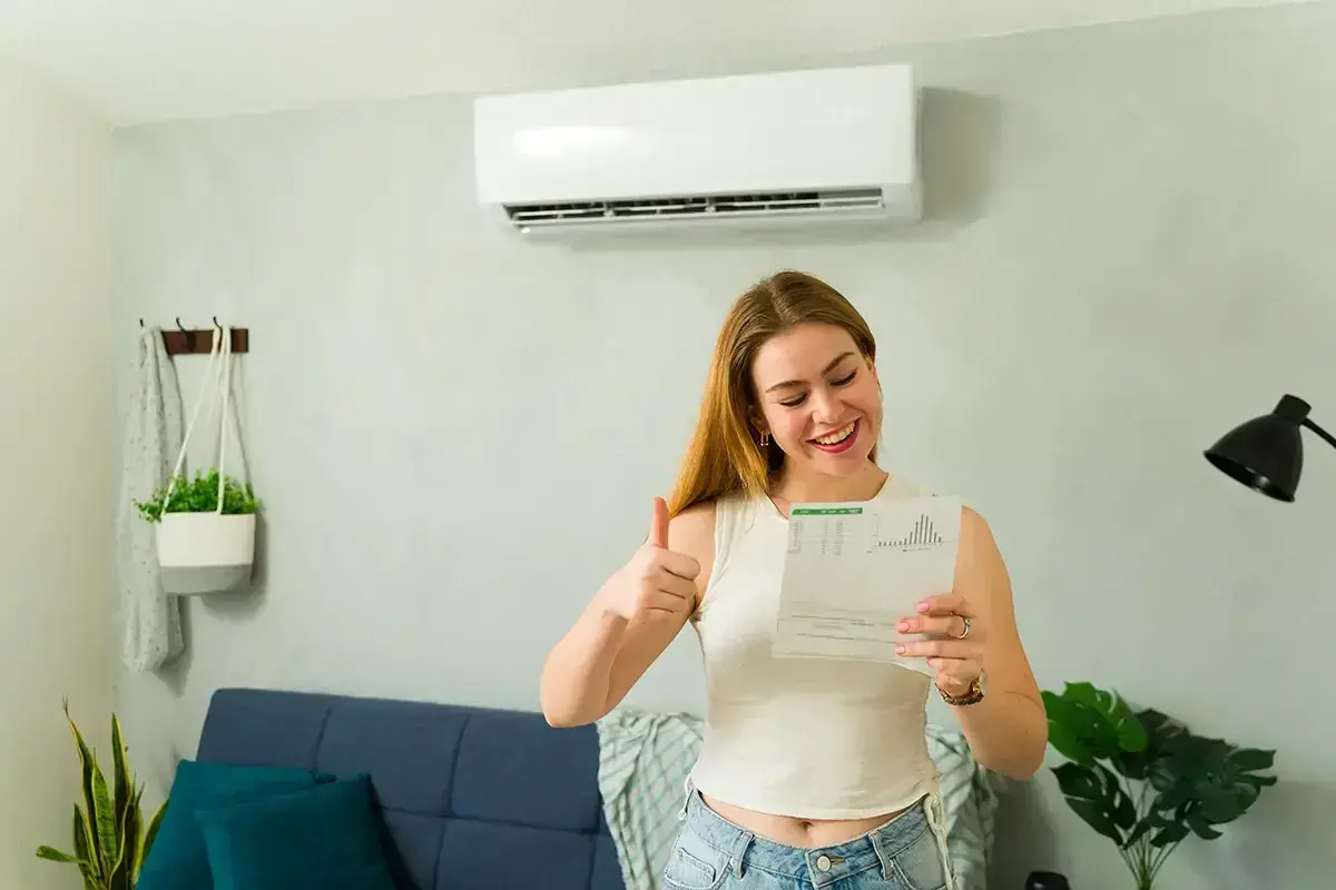 Uśmiechnięta kobieta z kciukiem w górze cieszy się z dokumentu, który może oznaczać dofinansowanie do klimatyzacji.