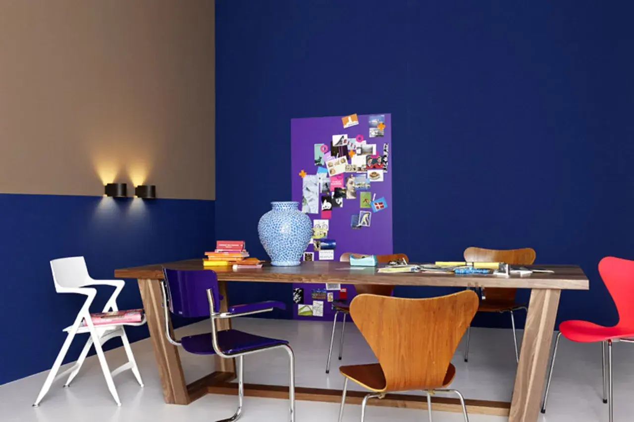 Zweifarbig gestrichene Wand in Blau und Beige mit einem Holztisch, bunten Stühlen und einer Pinnwand. Tolle wand zweifarbig streichen ideen!