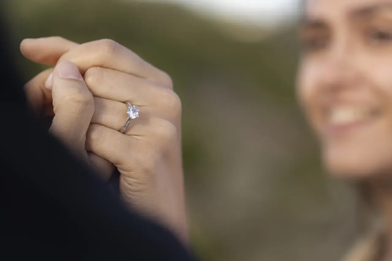 Delikatne pierścionki z diamentem, idealne jako pierścionki zaręczynowe. Biżuteria z diamentami na dłoni z jasnoróżowym manicurem.