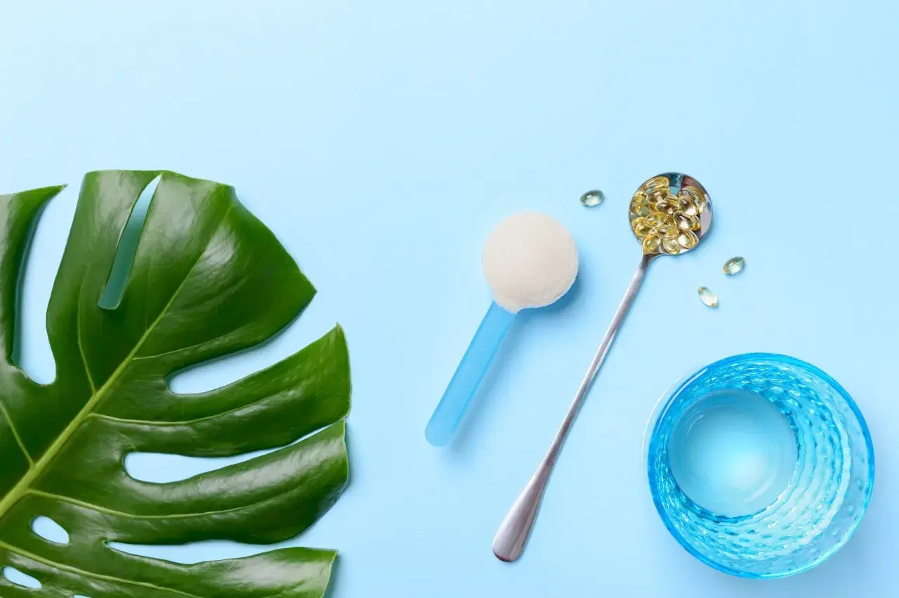 Grünes Monstera-Blatt, Löffel mit Kapseln, Pulver und Glas Wasser. Alles für die gleiche Wirkung.
