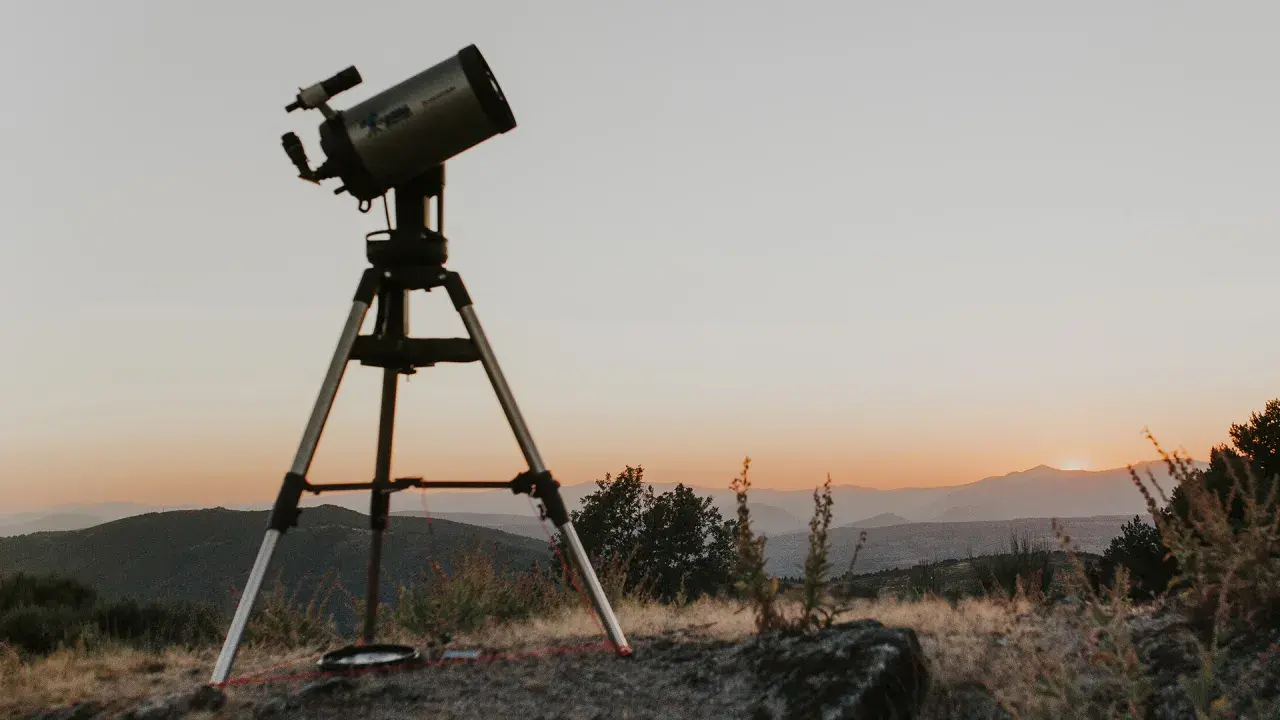 Telescopi preparat per a un sopar amb estrelles. El cel s'enfosqueix sobre les muntanyes, prometent una nit d'observació celestial.
