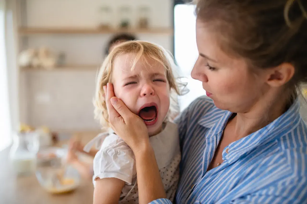Niña rubia llorando desconsoladamente mientras una mujer la consuela.