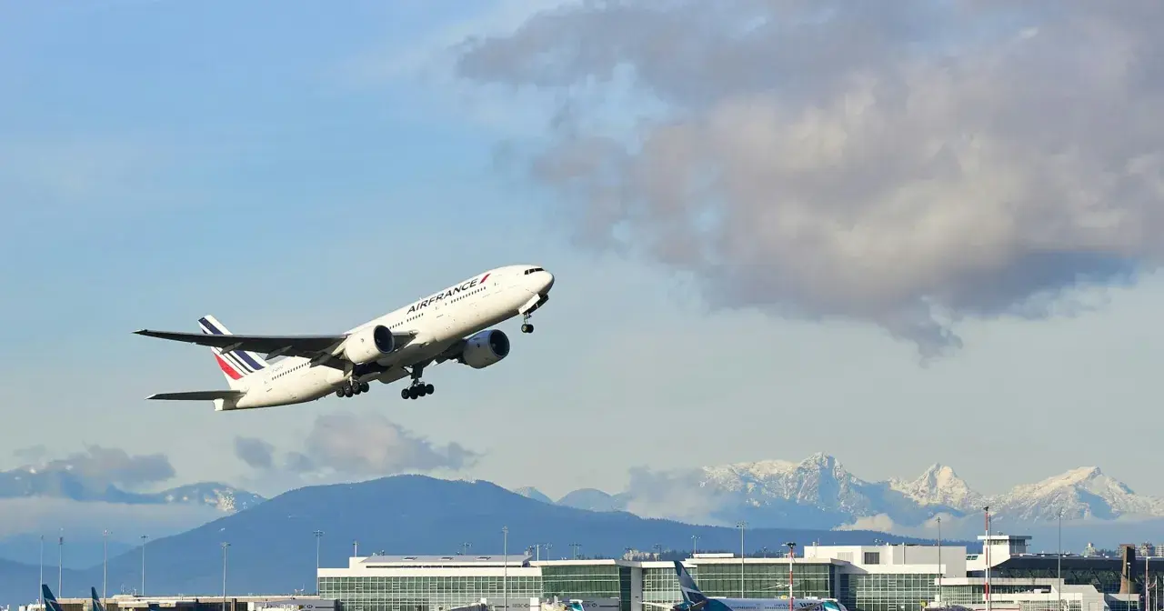 Samolot Air France wznosi się nad lotniskiem, a w tle widać ośnieżone góry. Idealny widok dla tych, którzy zastanawiają się, jak szukać lotów czarterowych.