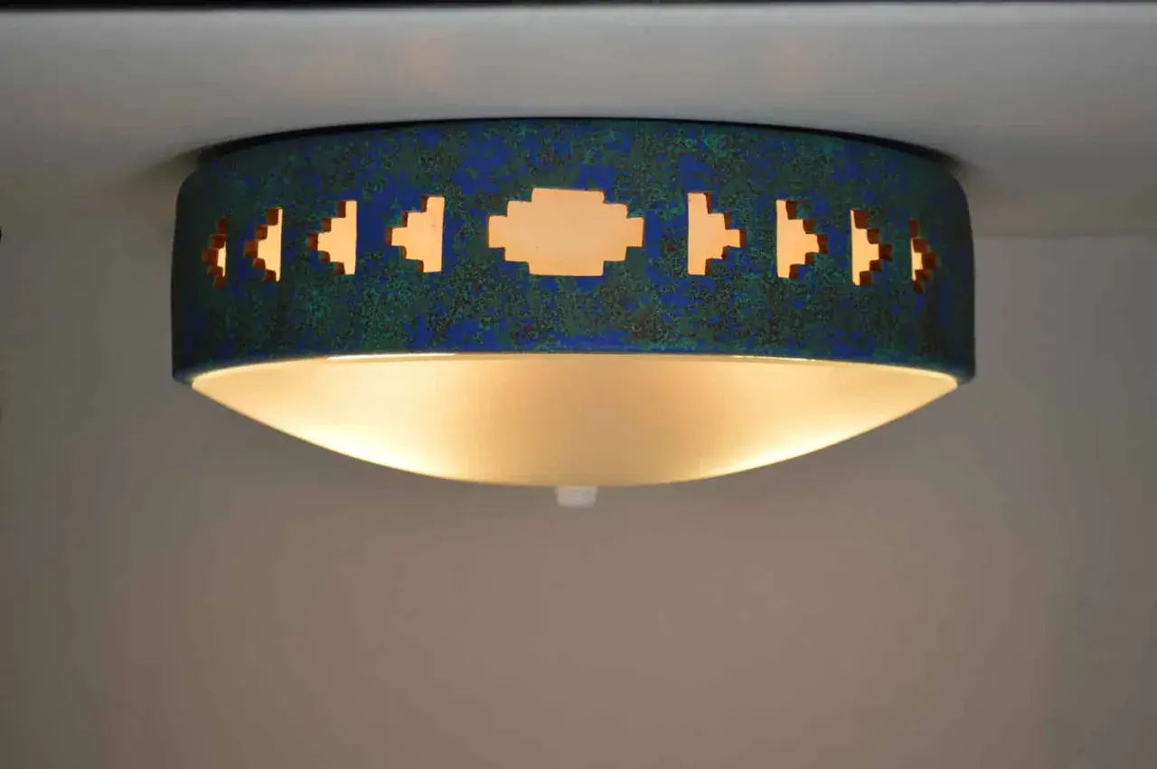 Lámpara techo azul turquesa con diseño geométrico calado, emite una luz cálida y acogedora.