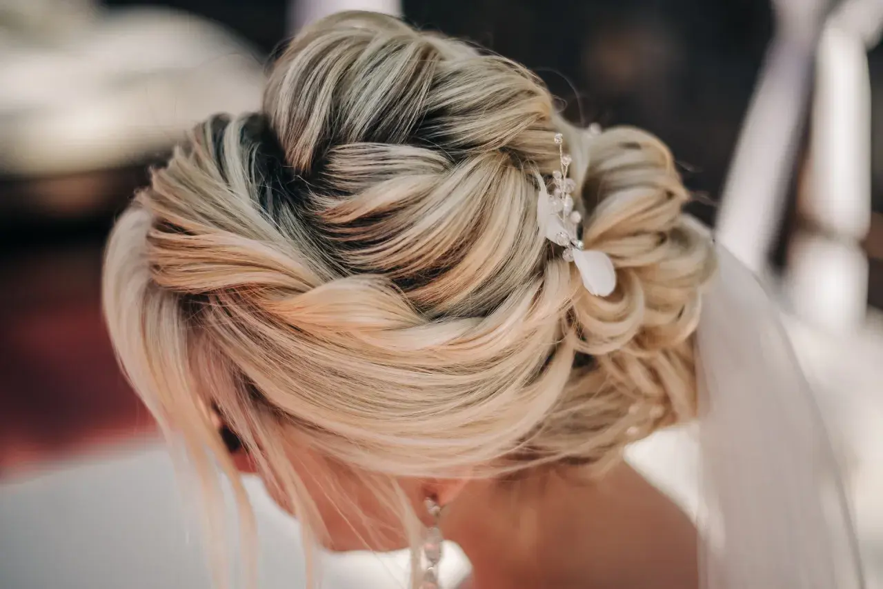 Elegancki, luźny warkocz ślubny z delikatną ozdobą z kryształków i piórka.